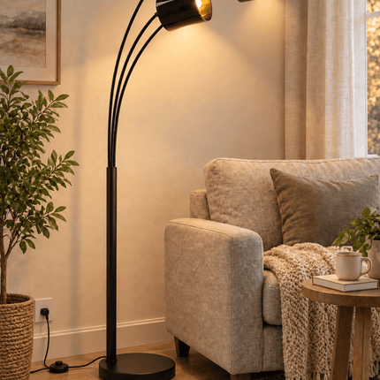 Black 3-light arc floor lamp with LED bulbs illuminated beside a living room armchair