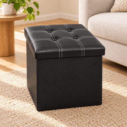 Black foldable storage footstool with padded tufted top in a living room