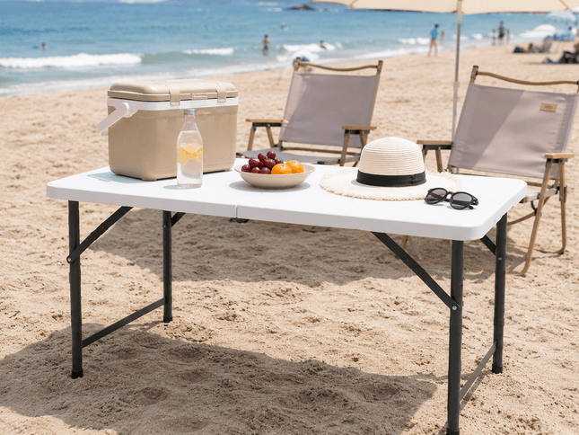 Portable folding camping picnic table on beach with outdoor chairs and picnic accessories