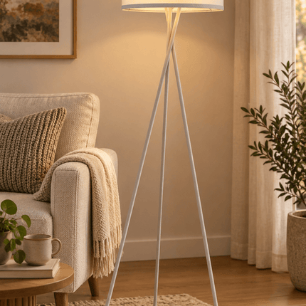 White tripod floor lamp with fabric shade and LED bulb in living room